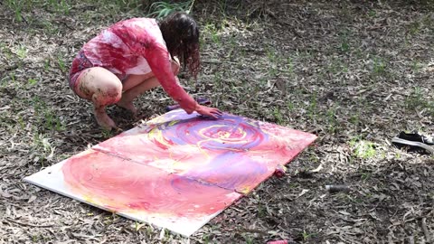 Painting by hand on the canvas laid across the forest floor