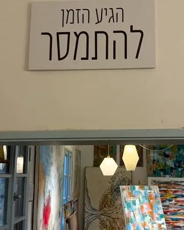 A sign reading 'time to let go' at the studio entrance, paintings behind it